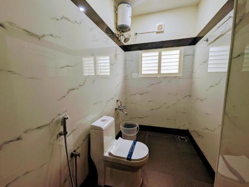 a bathroom with a toilet and a window at TPC Camphor in Tiruchchirāppalli