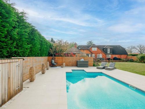 a swimming pool in a yard next to a fence at The Paddock - Luxury 5 Bed with Swimming Pool! in Ombersley