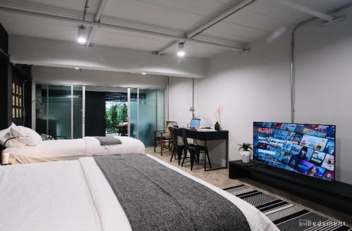 a bedroom with two beds and a flat screen tv at Bedsment in Chiang Rai