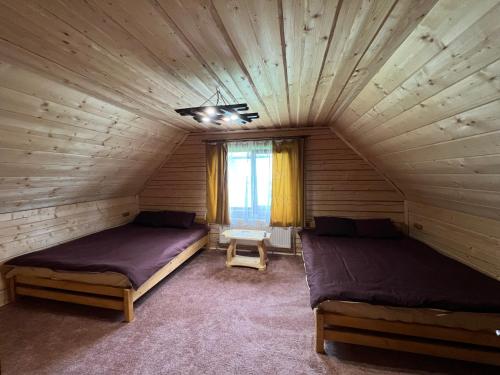 a bedroom with two beds in a wooden room at Котедж Mezohat in KozÊ¼meshchek