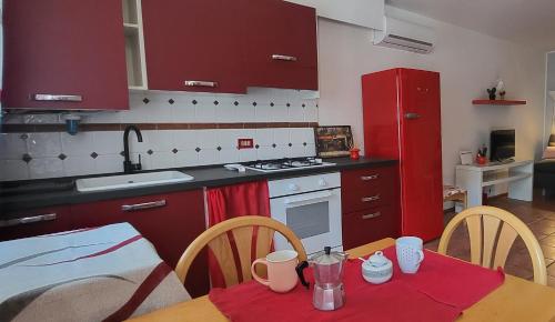una cucina con armadi rossi e un tavolo in legno con tavolo da pranzo di Alfa Appartamento in centro a Gorizia