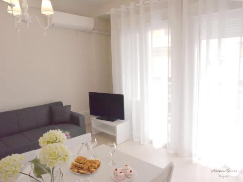 ein Wohnzimmer mit einem Sofa und einem Tisch mit Weingläsern in der Unterkunft Maria's Central Renovated Suites 2 in Alexandroupoli