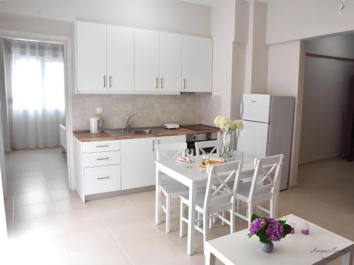 eine Küche mit weißen Schränken sowie einem Tisch und Stühlen in der Unterkunft Maria's Central Renovated Suites 2 in Alexandroupoli
