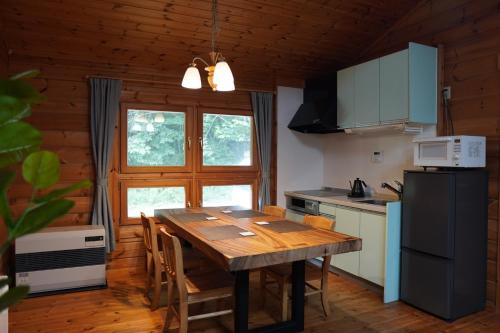 a kitchen with a wooden table and a refrigerator at ＯＮＶＯ ＳＴＡＹ ８ in Hokuto