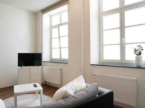 uma sala de estar com um sofá e duas janelas em Praktisch & modern - voll ausgestattetes Apartment em Stolberg