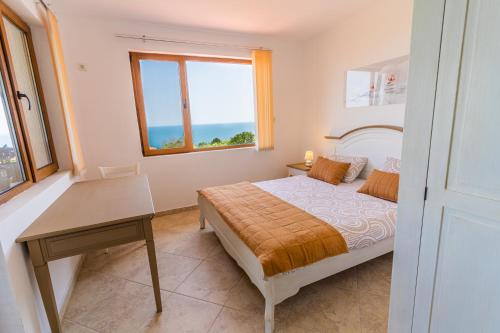 a bedroom with a bed and a desk and a window at Panorama Pearl Sea View in Balchik