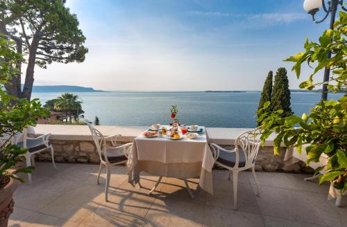 a table and chairs on a patio overlooking the water at Hotel Villa Florida & Suite Apartments in Gardone Riviera