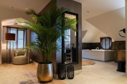 a bathroom with a large potted plant in front of a mirror at Hotel de Boskar Houthalen in Houthalen-Helchteren
