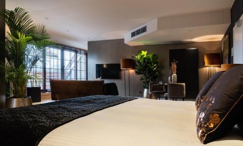 Aan de WolfsbergにあるHotel de Boskar Houthalenのベッドとリビングルームが備わるホテルルームです。