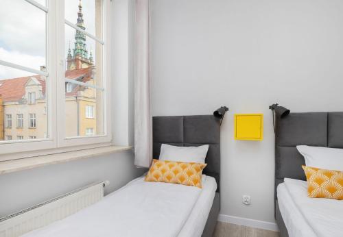 two beds in a room with a window at CITYSTAY Starówka Apartament in Gdańsk
