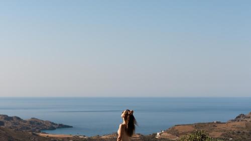 a woman standing on a cliff looking out at the ocean at Sunrise Villa, a Secluded Gem in South Crete, By ThinkVilla in Marioú