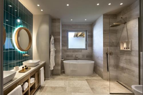 a bathroom with a tub and two sinks and a mirror at Hotel La Bisaccia in Baja Sardinia