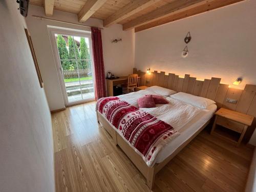 een slaapkamer met een bed en een groot raam bij Affittacamere Famiglia Ceschini in Tesero