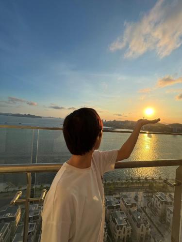 a person standing on a balcony looking at the sunset at Hoa Homestay Hạ Long 2909 in Ha Long