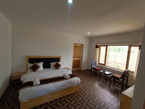 a bedroom with a large bed and a large window at Zlatan Guest House in Leh