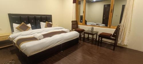 a bedroom with two beds and a table and a mirror at Zlatan Guest House in Leh