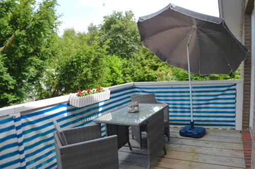 une table et des chaises avec un parasol sur une terrasse dans l'établissement Brigg im Schiffehaus, à Wangerland