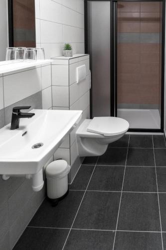 a white bathroom with a sink and a toilet at Penzion Golf Luby in Luby