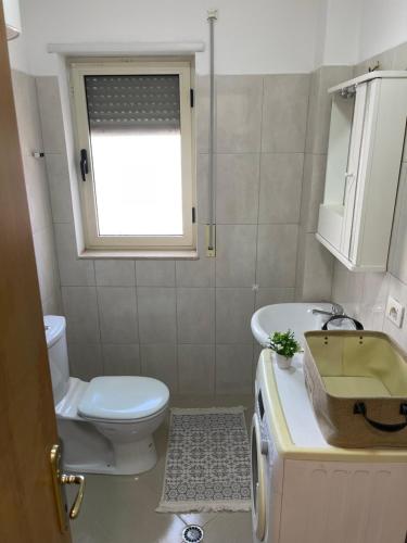 La salle de bains est pourvue de toilettes, d'un lavabo et d'une fenêtre. dans l'établissement Sunrise Golem Summer Apartment, à Durrës