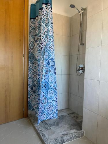 La salle de bains est pourvue d'une douche et de carrelage bleu et blanc. dans l'établissement Sunrise Golem Summer Apartment, à Durrës