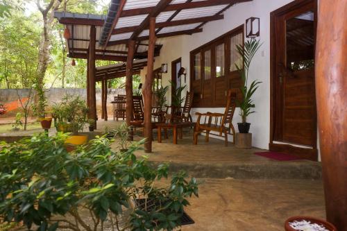a porch of a house with chairs and tables at Flash Rock Villa in Sigiriya