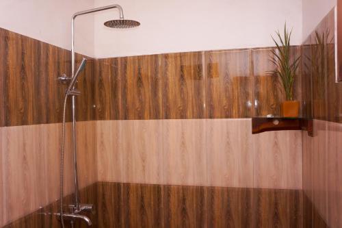 a bathroom with a shower with a wooden wall at Flash Rock Villa in Sigiriya