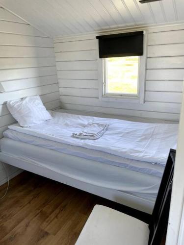a white bed in a room with a window at Stuga med panoramautsikt, paradis för fågelskådare och vandrare, självstäd efter besök in Mörbylånga