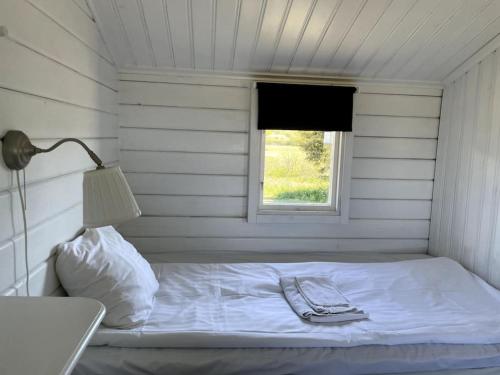 a bed in a white room with a window at Stuga med panoramautsikt, paradis för fågelskådare och vandrare, självstäd efter besök in Mörbylånga