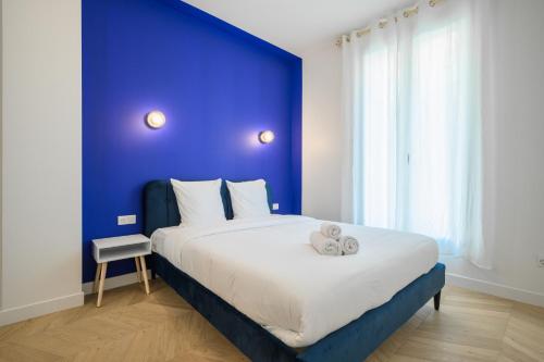une chambre avec un grand lit avec un mur bleu dans l'établissement Le Walesa, magnifique 3P, spacieux et rénové, Port de Nice, à Nice
