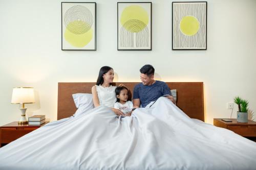 a woman and a man and a child sitting in bed at MekongView 3 CondoTel in Phnom Penh