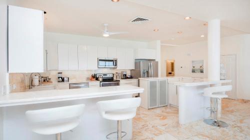 a large white kitchen with white cabinets and white stools at Laguna Del Mar in George Town