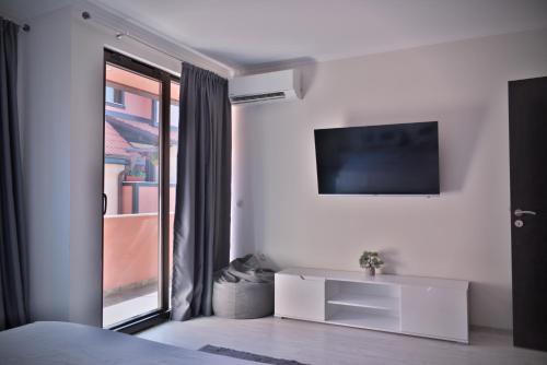 a white bedroom with a tv on the wall at Medius Park Apartment in Sandanski