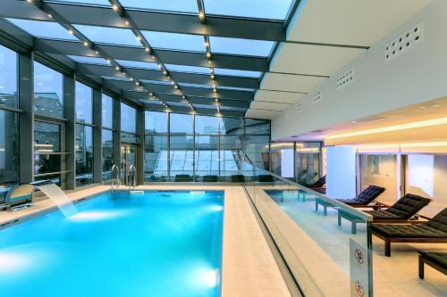een groot zwembad in een gebouw met ramen bij Sheraton Bucharest Hotel in Boekarest