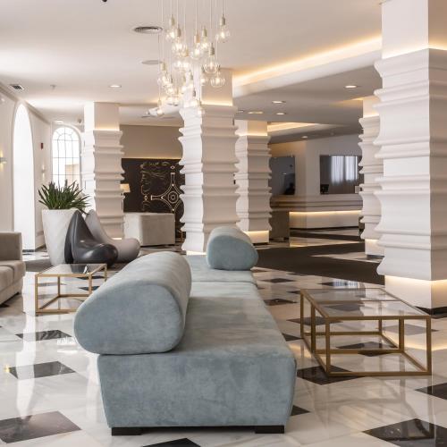 a lobby with a couch and tables and a chandelier at Monte Triana in Seville