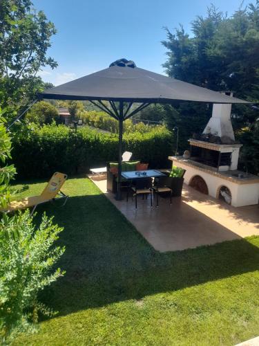 a patio with an umbrella and a table and a grill at Beautiful Summer Villa in Chalkoutsi in Khalkoútsion