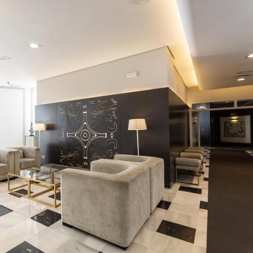 a lobby with a couch and chairs and a wall at Monte Triana in Seville