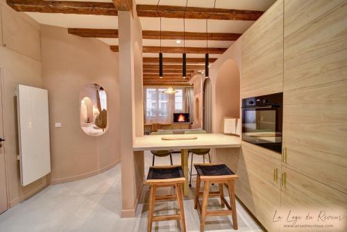 una cocina con armarios de madera y una barra con taburetes en La Loge du Rêveur - Spa - Vieux-Lyon en Lyon