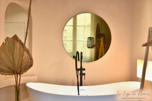 a bath tub in a bathroom with a round mirror at La Loge du Rêveur - Spa - Vieux-Lyon in Lyon