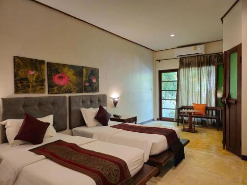 a hotel room with two beds and a table at Baan Panwa Resort in Panwa Beach