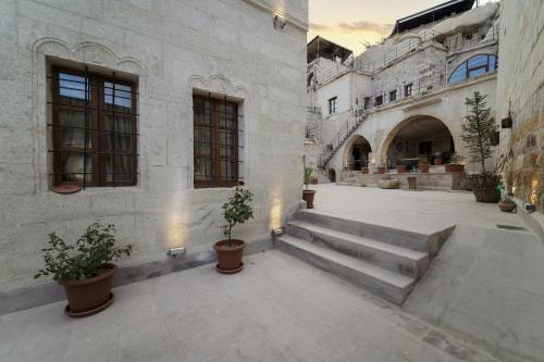 a courtyard with potted plants and stairs in a building at Göreme Escape Cave Suites in Goreme