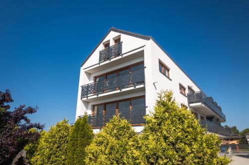 a white building with trees in front of it at SOLEK Apartamenty i pokoje gościnne in Mielno