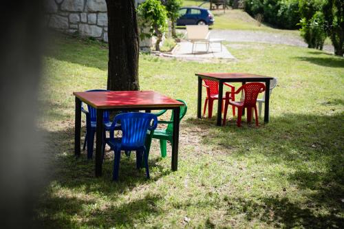 four tables and chairs in the grass near a tree at Villa tra montagna e laghi 14 posti in Crone