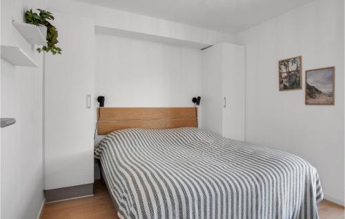 a bed in a white room with a striped blanket at Havnehusene, Lejl 41 in Engvang