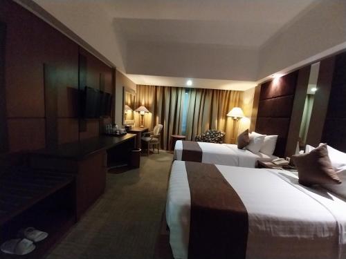 ein Hotelzimmer mit 2 Betten und einem Schreibtisch in der Unterkunft Horison Ultima Menteng Jakarta in Jakarta