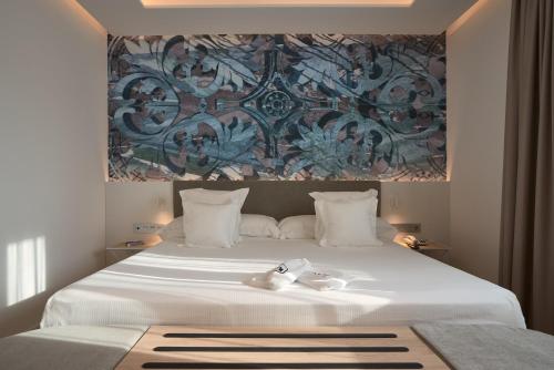 a bedroom with a large white bed with a painting on the wall at Monte Triana in Seville
