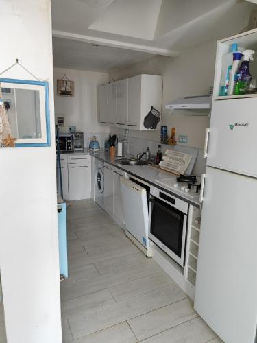 Il comprend une cuisine équipée d'appareils électroménagers blancs et d'un réfrigérateur blanc. dans l'établissement Détente, à Saint-Georges-de-Didonne
