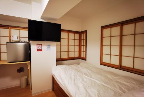 a room with a bed and a television on a wall at Hostel Belle Via Tokyo in Tokyo