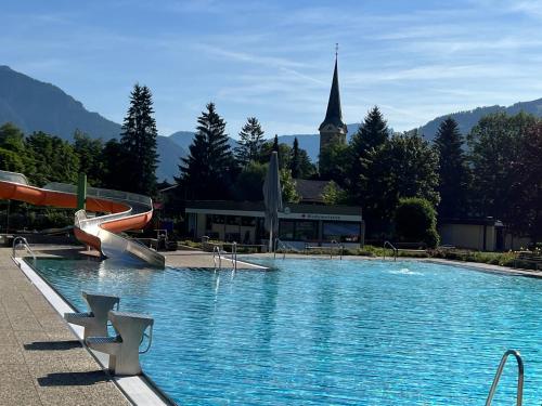 a large swimming pool with a church in the background at Gästehaus-Pension Bendler in Kirchdorf in Tirol