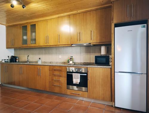 a kitchen with wooden cabinets and a white refrigerator at Casa dos Côtos. in Castro Laboreiro
