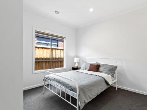 a white bedroom with a bed and a window at Sara by Ready Set Stay in Caroline Springs